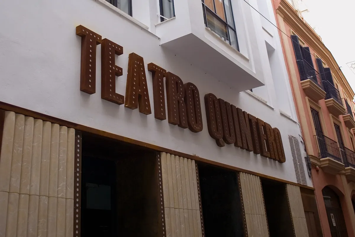 Bílá fasáda bývalého Teatro Quintero na Calle Cuna v Seville, s velkými rezavě zbarvenými písmeny tvořícími starý název divadla nad vchodem